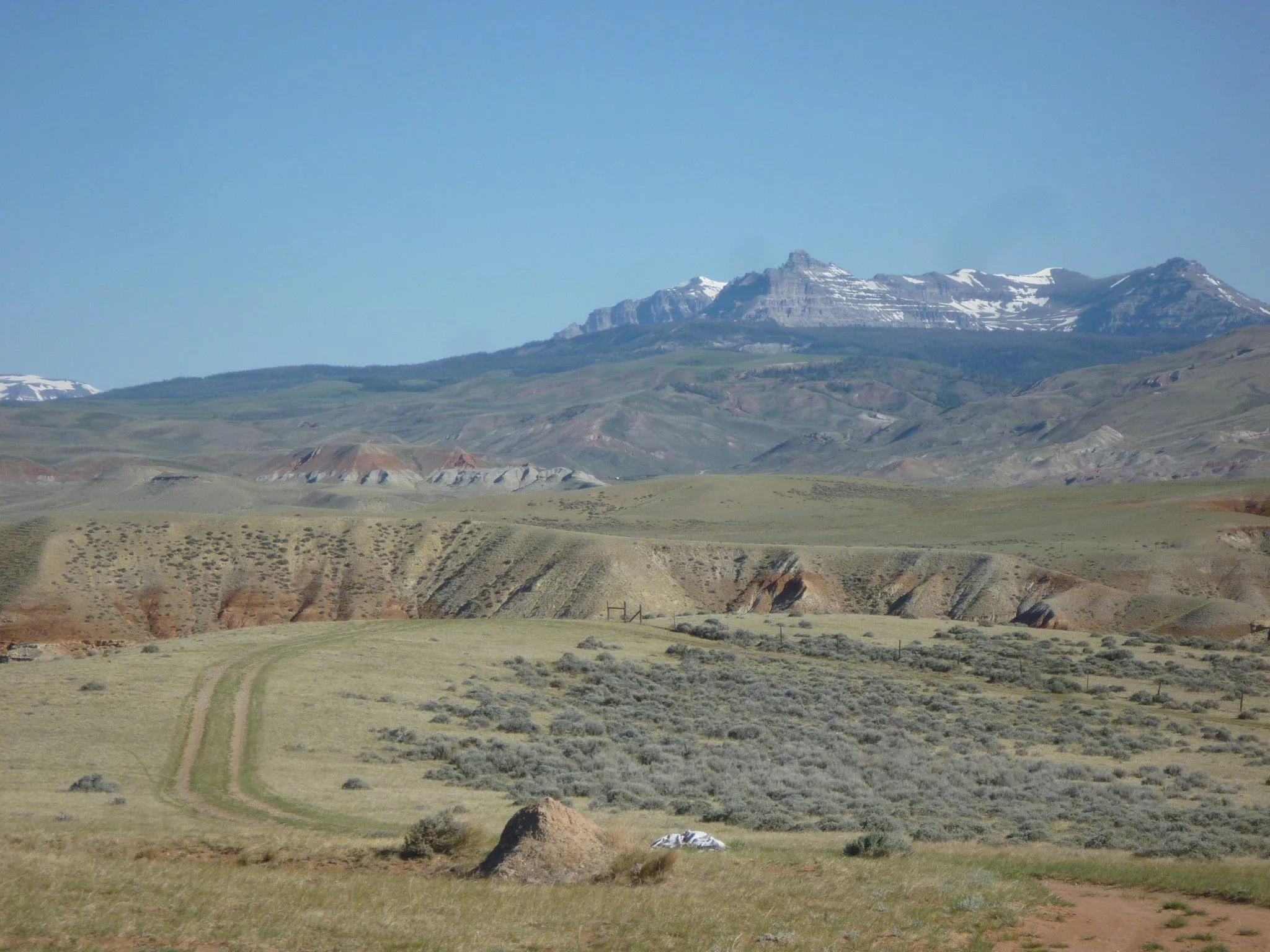 Sagebrush flats and red badlands below snow-capped mountains in Wyoming
